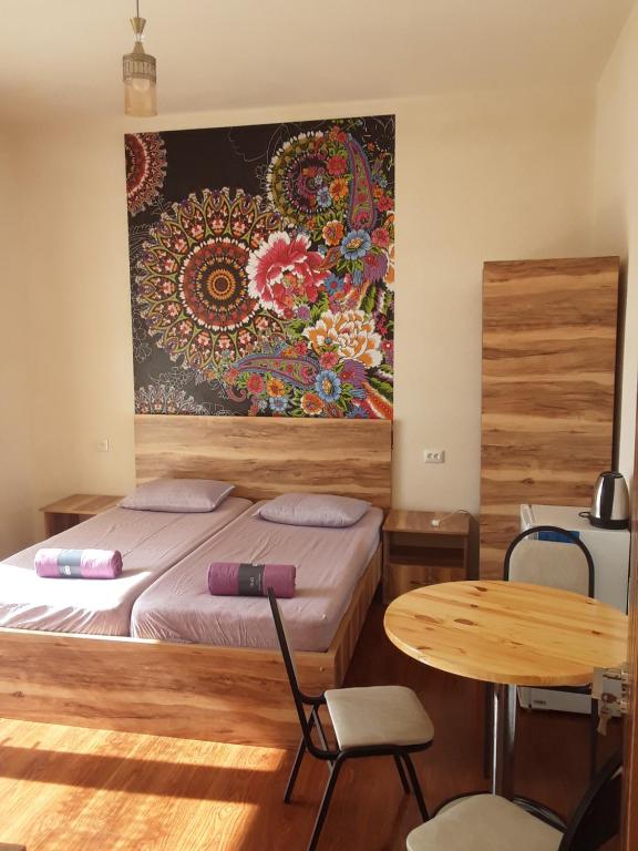 ein Schlafzimmer mit einem Bett und einem Tisch sowie einem Gemälde an der Wand in der Unterkunft Guest House Buche on Agmashenebeli 219 in Kobuleti
