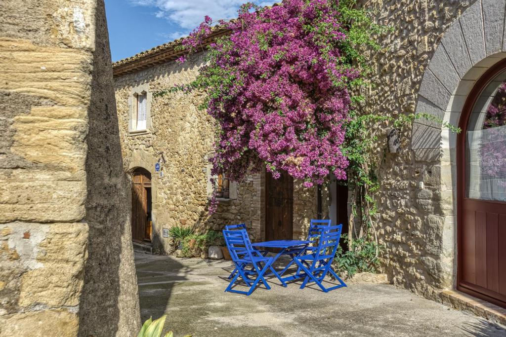 Deux chaises bleues et une table en face d'un bâtiment avec des fleurs violettes dans l'établissement Casa Blava, à Orriols