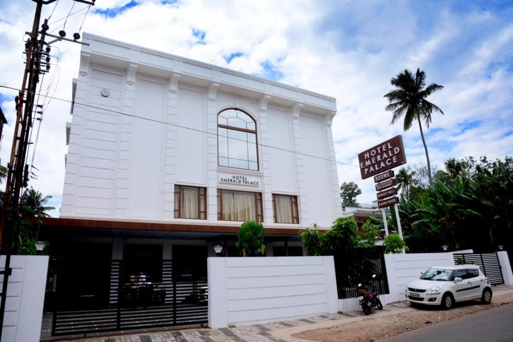 un bâtiment blanc avec un panneau devant lui dans l'établissement HOTEL EMERALD PALACE, à Kottiyam