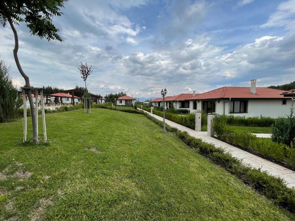 a green yard with houses in the background at Enigma Complex in Pavel Banya