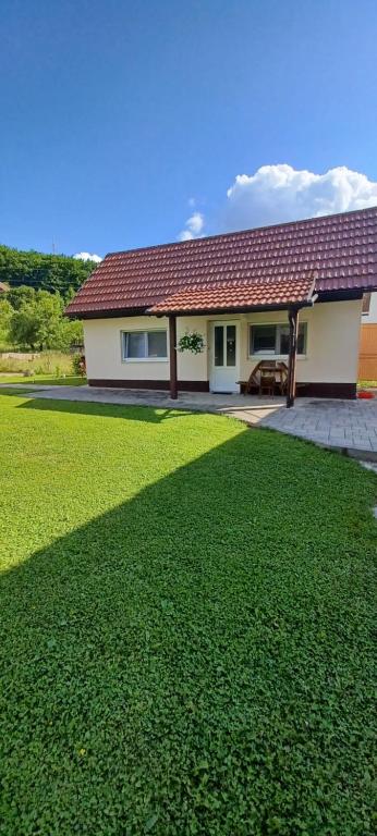 a house with a green lawn in front of it at A&M studio apartman in Otočac