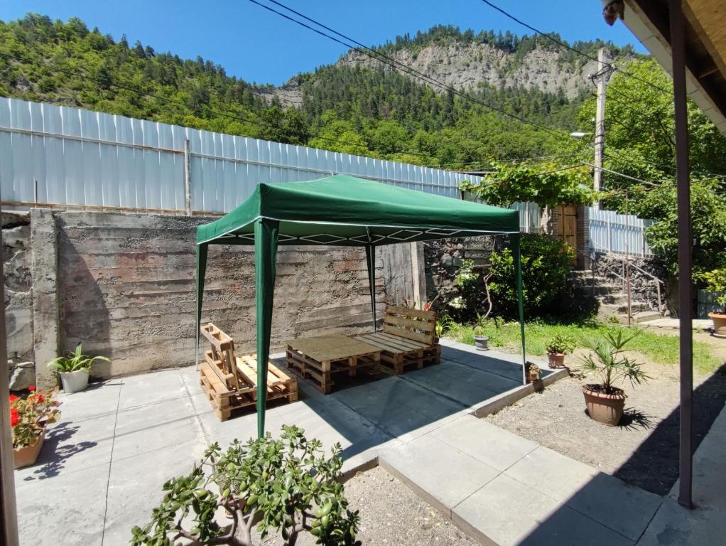 a green umbrella and benches in a yard at ATI MTA - Eco Hostel in Borjomi