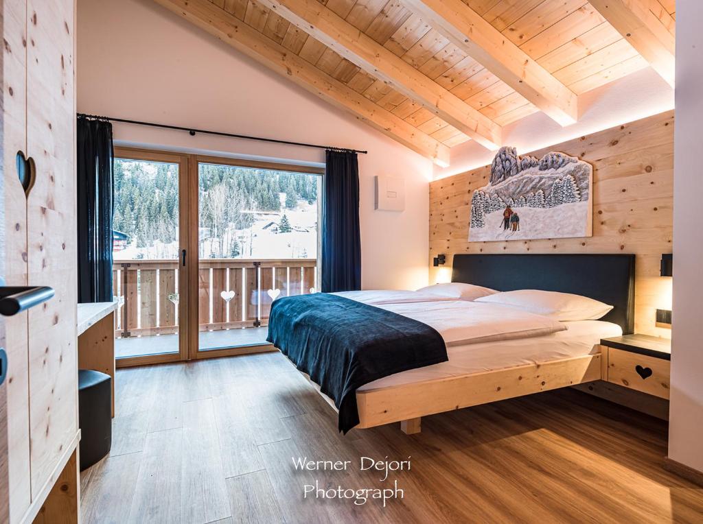 a bedroom with a bed and a large window at Piciulei Pitl in Selva di Val Gardena