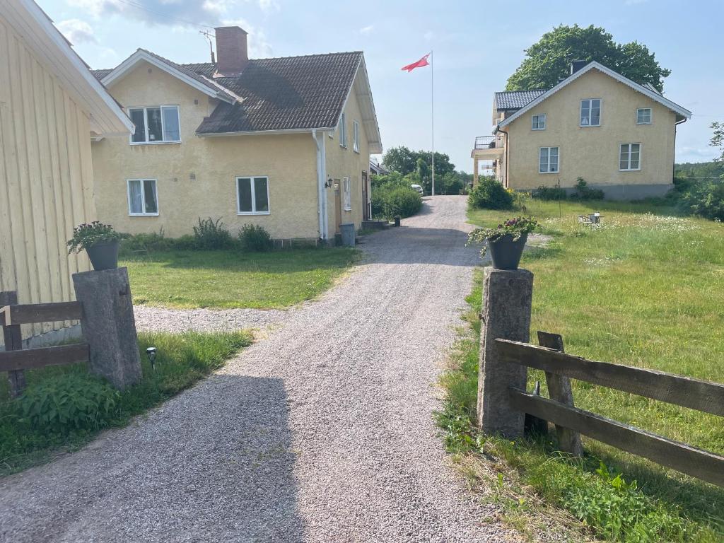 a dirt road next to a house with a fence at Patterdale farm holiday apartments in Gamleby