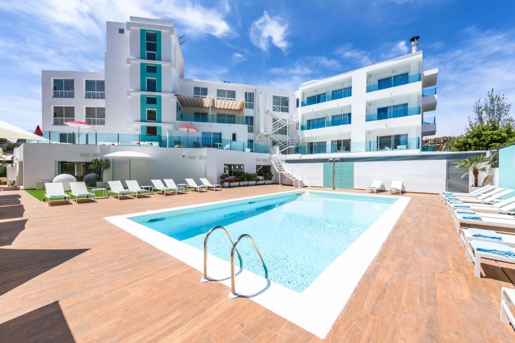a swimming pool with chairs and a building at Plaza Santa Ponsa Boutique - Adults Only. in Santa Ponsa