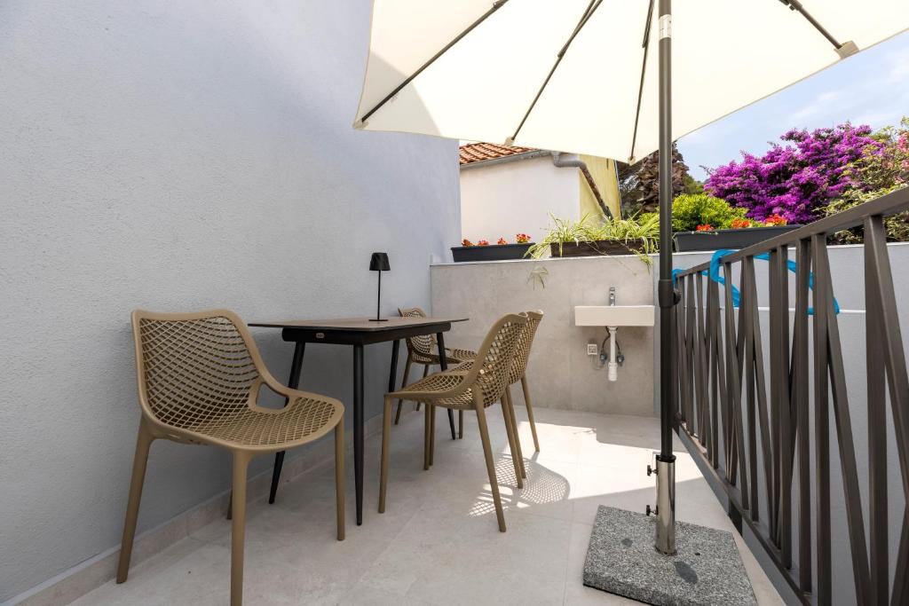 a patio with a table and chairs and an umbrella at Casa Maginja - Mediterranean Old Town Apartments in Veli Lošinj