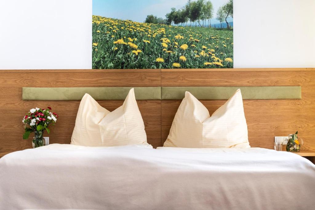 1 cama con almohadas blancas y un campo de flores en Gastwirtschaft Hold, en Mönichwald