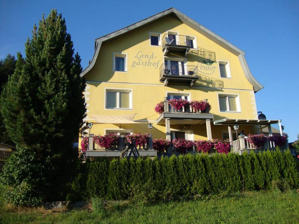 un gran edificio amarillo con cajas de flores. en Landgasthof Lenzer en Strassen