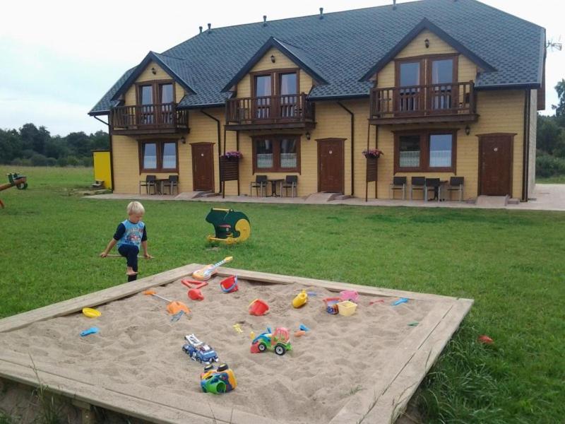 a child playing in a sandbox in front of a house at Domki Biały Łabędź in Jarosławiec