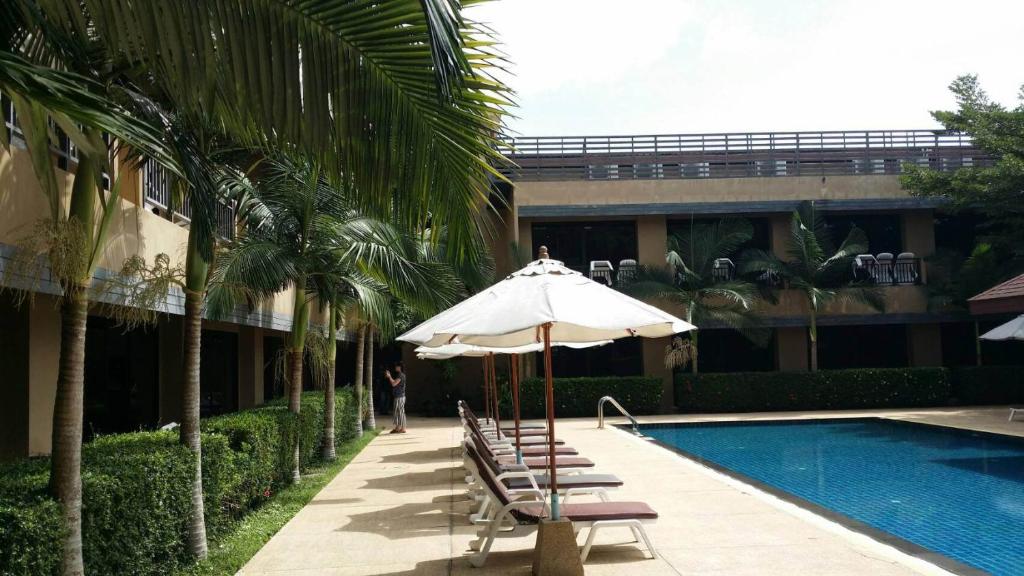 una piscina con sillas y una sombrilla junto a un edificio en Naiyang Beach Hotel SHA Plus, en Nai Yang Beach