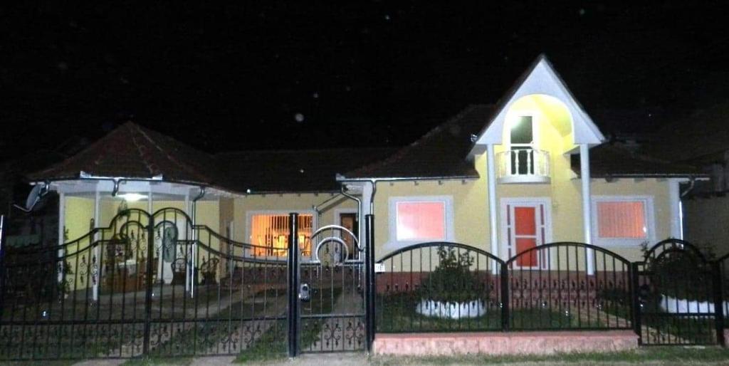 a yellow and white house with a gate at night at Casa Elisei in Asău