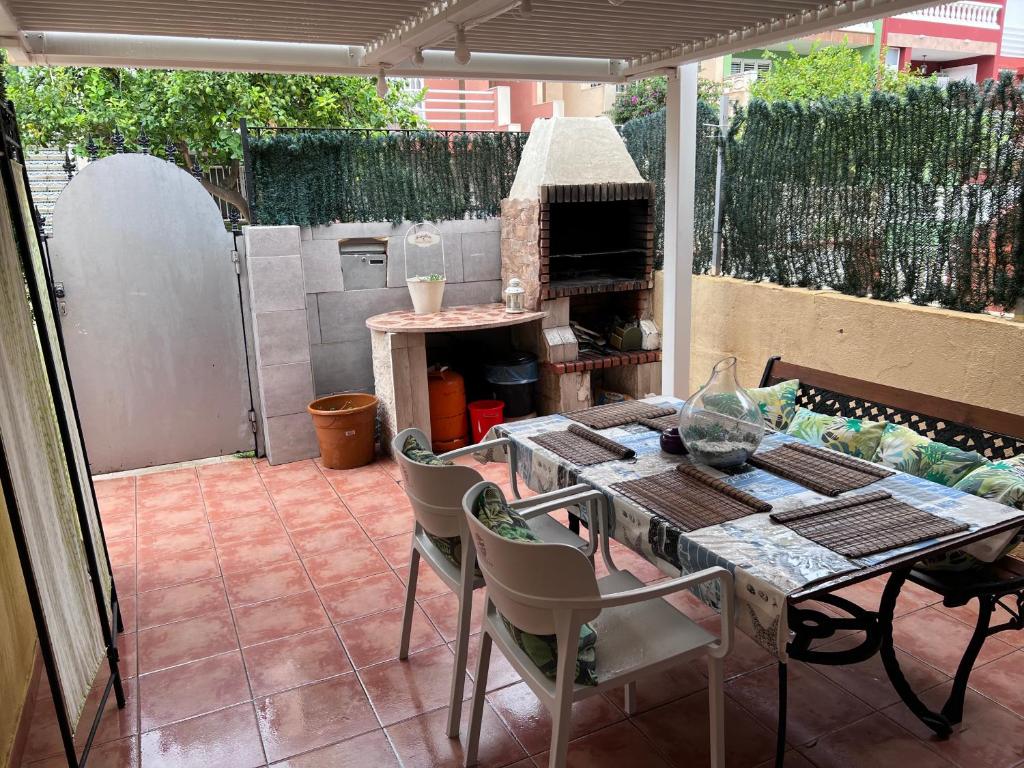 un patio con mesa, sillas y parrilla en Barbacoa Villaedu, en La Pobla de Farnals