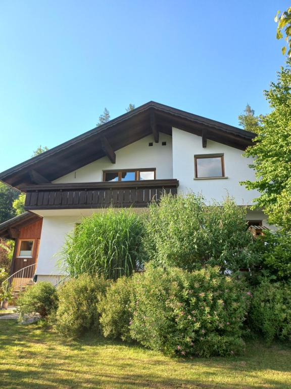 uma casa branca com um telhado preto e alguns arbustos em Ferienwohnung in Schwarzach Vorarlberg em Schwarzach