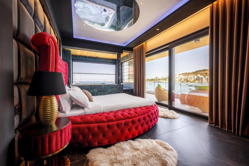 ein Schlafzimmer mit einem Bett mit einer roten Ottomane in der Unterkunft Ushuaia Playa Xemxija Boutique Hotel in St Paul's Bay
