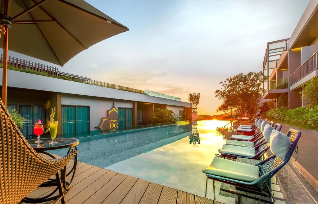 - une piscine avec des chaises longues et un parasol dans l'établissement Fusion Suites Phuket Patong, à Patong Beach