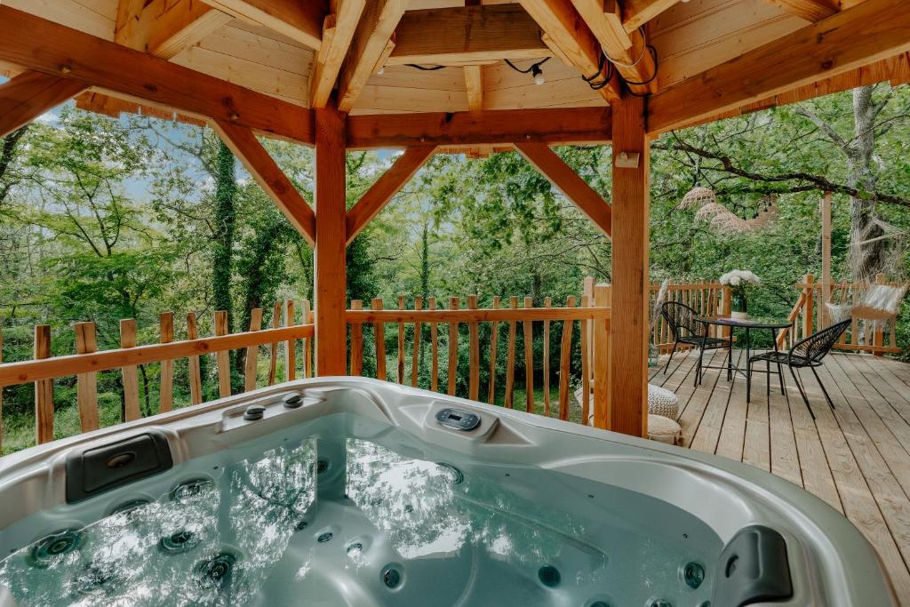 eine Whirlpool-Badewanne auf einer Holzterrasse in der Unterkunft Les Cabanes Girondines-Lodges & Spa in Martillac