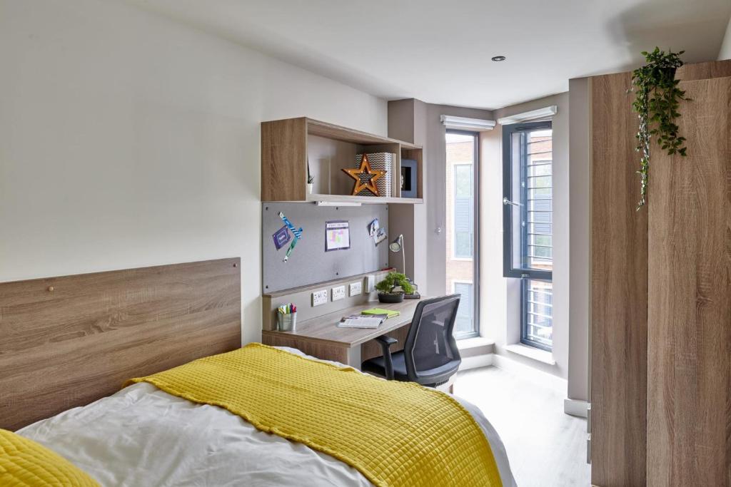 1 dormitorio con escritorio y 1 cama con manta amarilla en Modern Ensuites with Shared Kitchen at Howard Gardens in Cardiff, en Cardiff