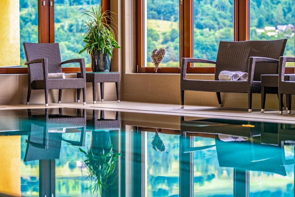 um quarto com cadeiras e uma mesa com um reflexo na água em Relax Resort Hotel Kreischberg em Sankt Georgen ob Murau