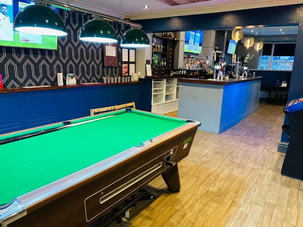 a pool table in a room with a bar at Letting Rooms @ Charles Dickens in Wigan