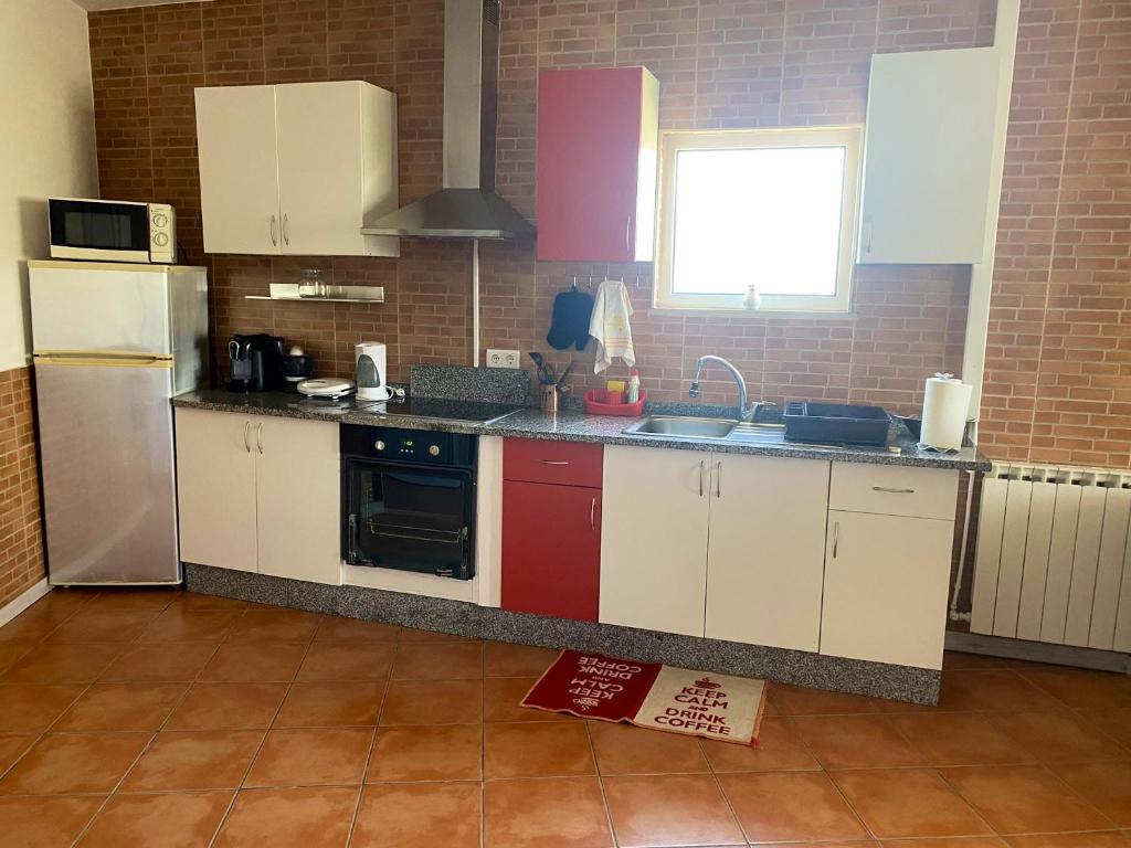 een keuken met witte kasten, een wastafel en een koelkast bij 2 bedrooms house with enclosed garden and wifi at Ponte de Vagos in Ponte de Vagos