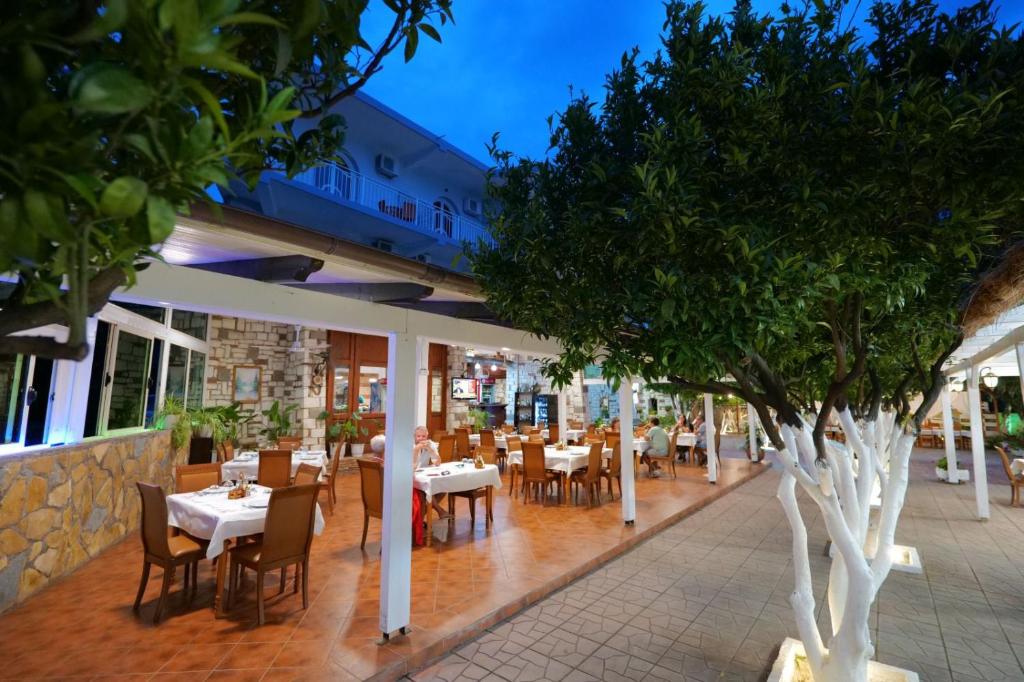 een restaurant met tafels, stoelen en bomen bij Hotel Nika Radhime in Vlorë