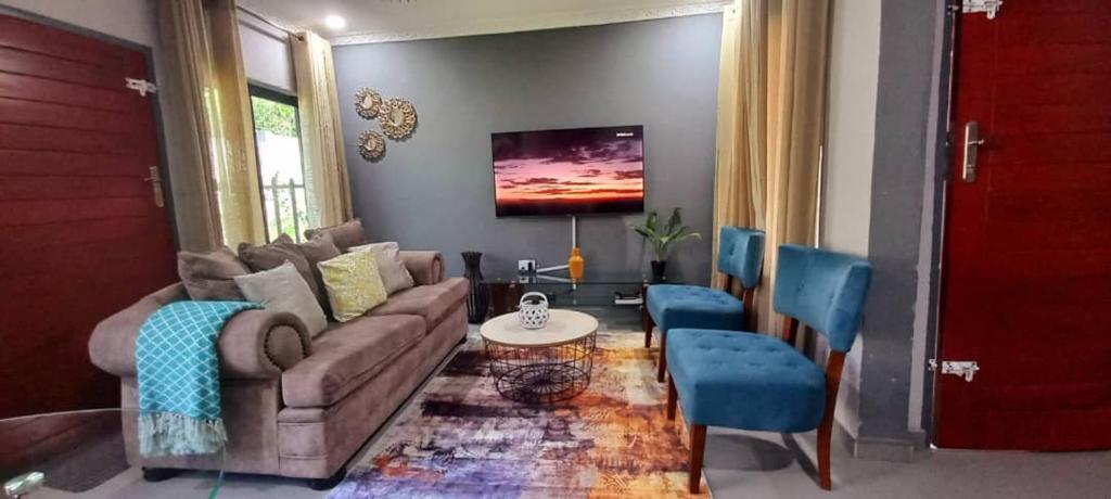 sala de estar con sofá y sillas azules en Zachi Apartments en Kitwe