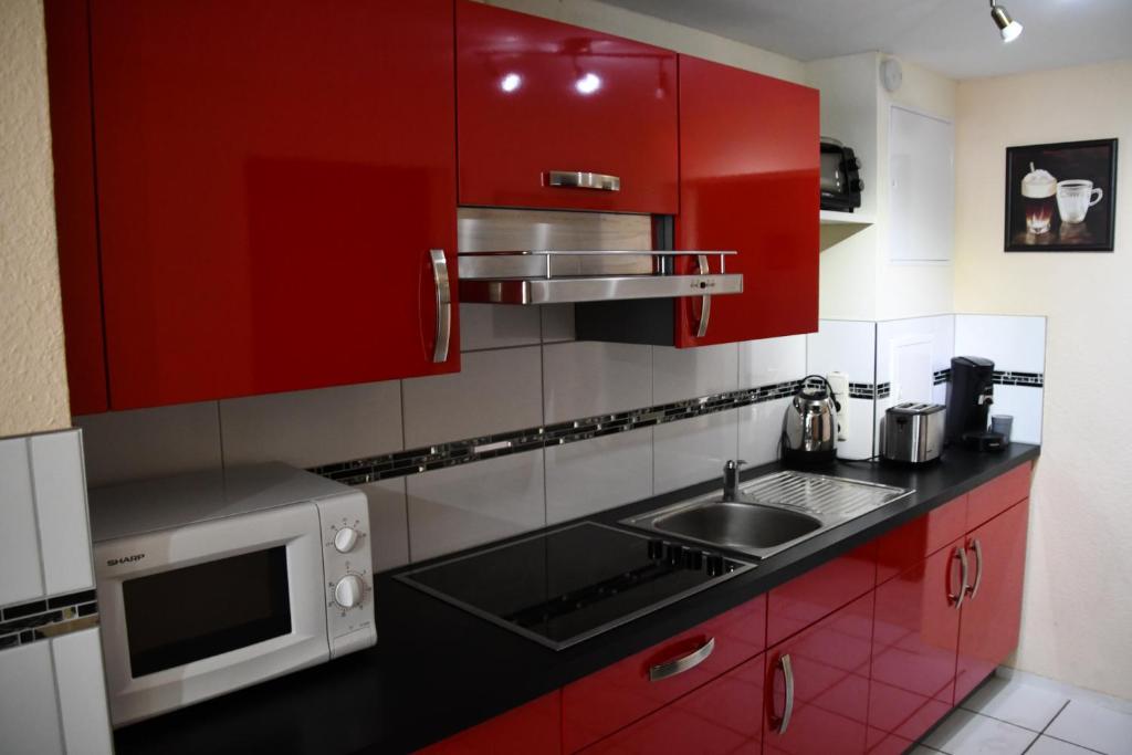 uma cozinha vermelha com um lavatório e um micro-ondas em B&M Apartment em Zierenberg