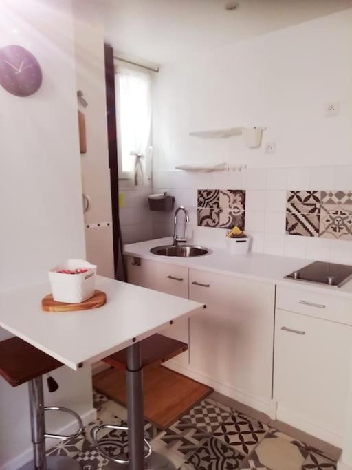 a white kitchen with a sink and a counter at L&#39;Ornella Dom Studio en copropriété in Marseille