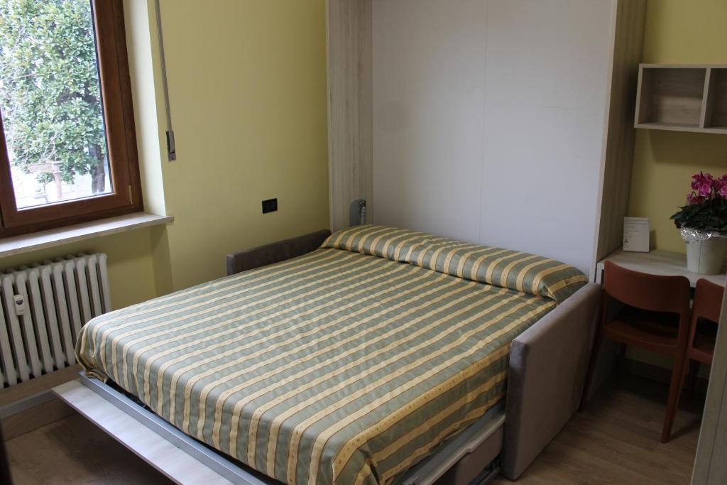 Bett in einem Zimmer mit einem Tisch und einem Fenster in der Unterkunft Residence La Noce con Angolo Cottura in Chivasso