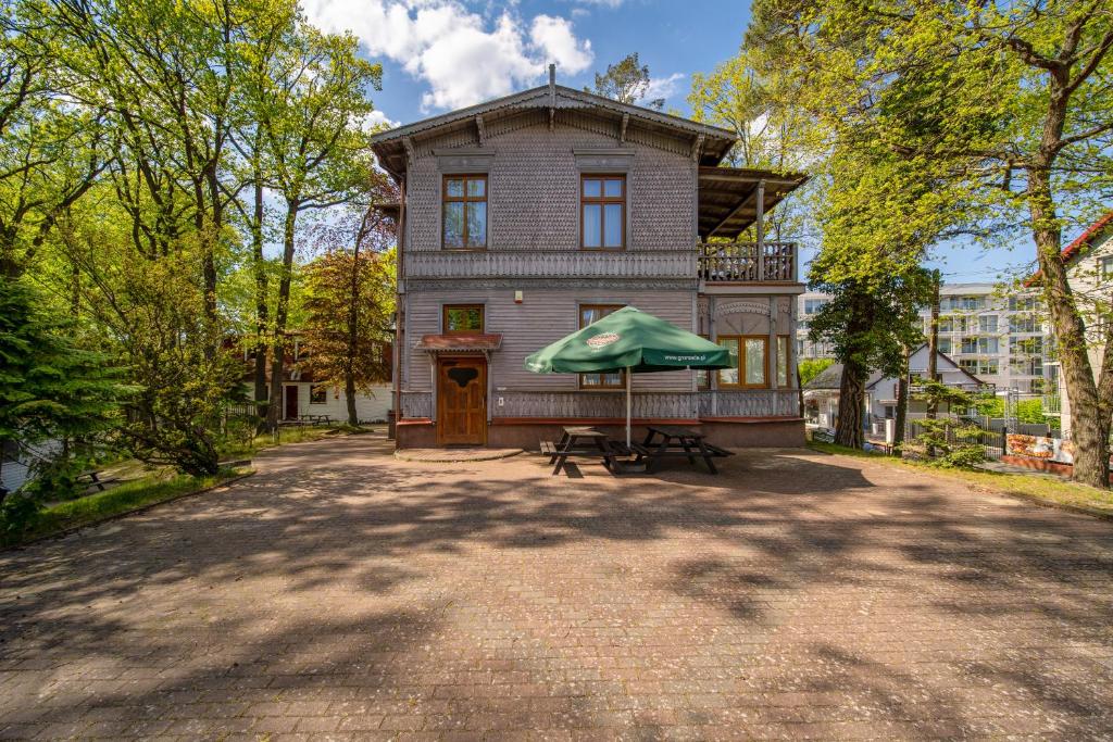 uma casa com um guarda-chuva verde em frente em Apartament w willi Rybitwa em Międzyzdroje
