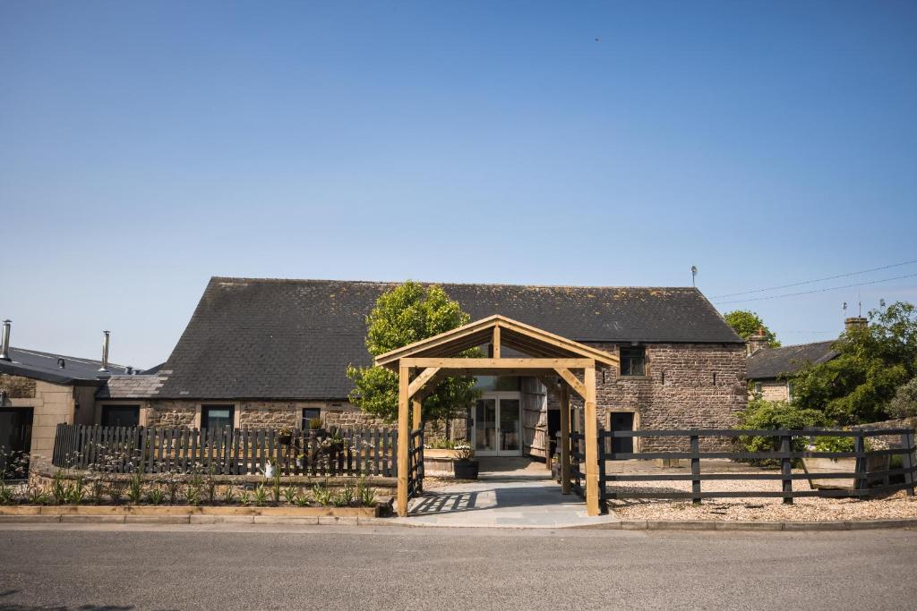 a stone house with a wooden archway in front of it at Bashall Barn in Clitheroe