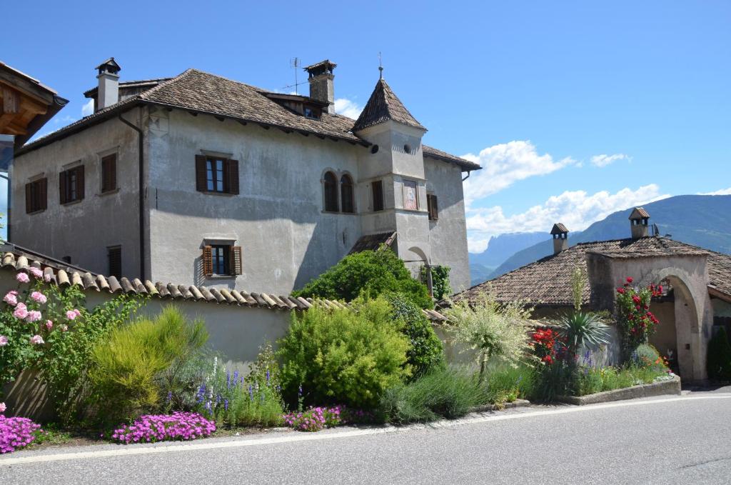 a large house with flowers in front of a street at Ansitz Weissenheim in Appiano sulla Strada del Vino