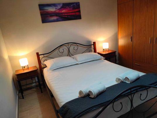 een slaapkamer met een groot wit bed met 2 lampen bij PANOS HOUSE in Mákri