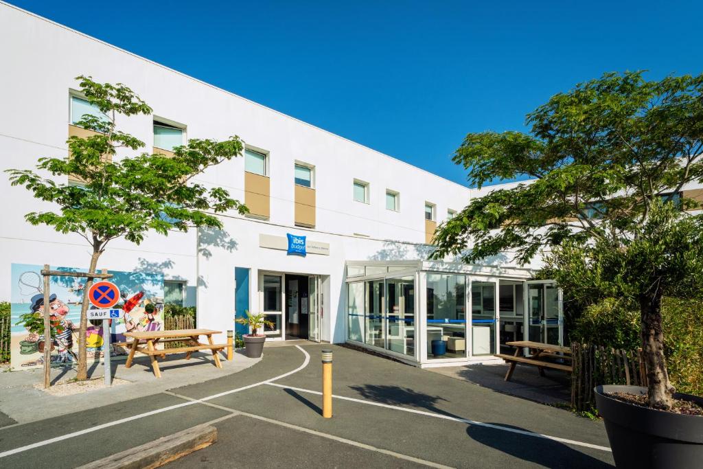 um edifício branco com bancos à sua frente em Ibis budget Les Sables d'Olonne em Les Sables-dʼOlonne