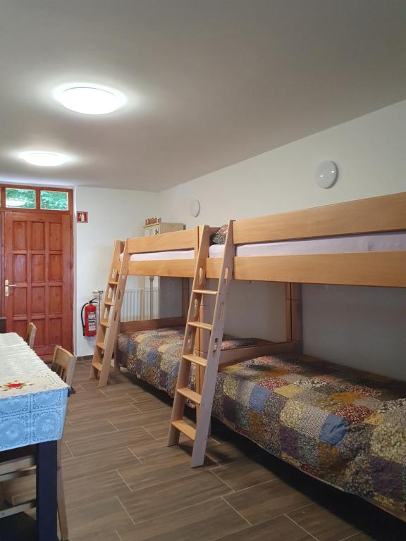 a room with three bunk beds and a table at Hiška pri Tisi in Ptujska Gora