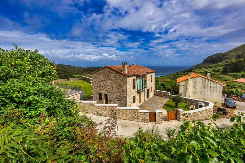 an old stone house on the side of a hill at Sal de Mar Apartamentos in Muxia