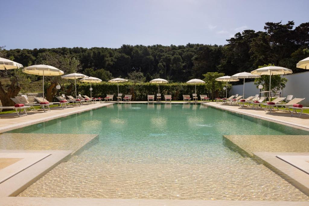 a swimming pool with chairs and umbrellas at Masseria Bandino & Spa in Otranto