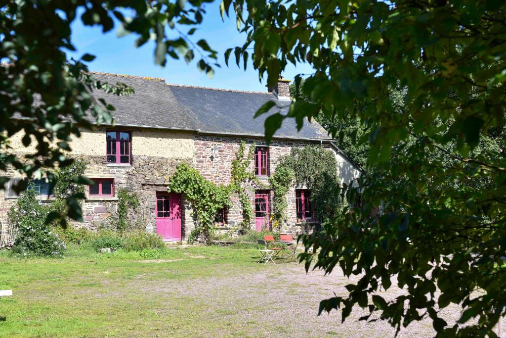 une ancienne maison en pierre avec une porte rose dans l'établissement La Maison des Hirondelles Forêt de Brocéciande, à Saint-Malon-sur-Mel