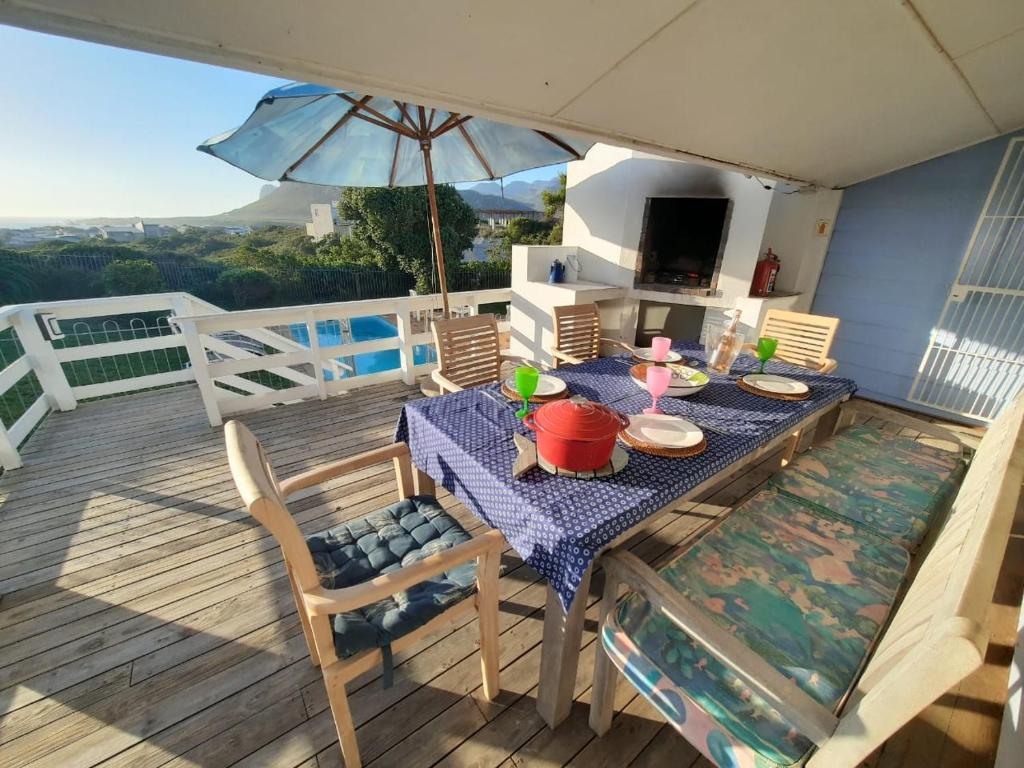 einen Tisch und Stühle auf einer Terrasse mit einem Sonnenschirm in der Unterkunft The Mermaid's Tail in Pringle Bay