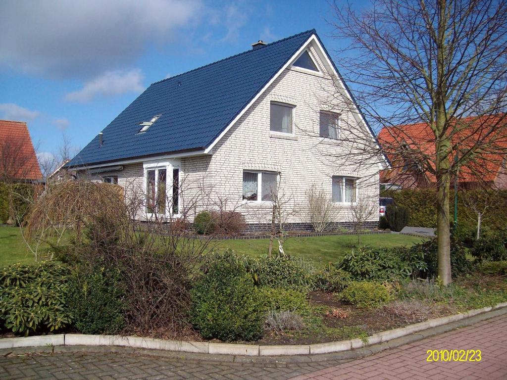 a white house with a blue roof at Ferienwohnung Am Walde 35177 in Hesel