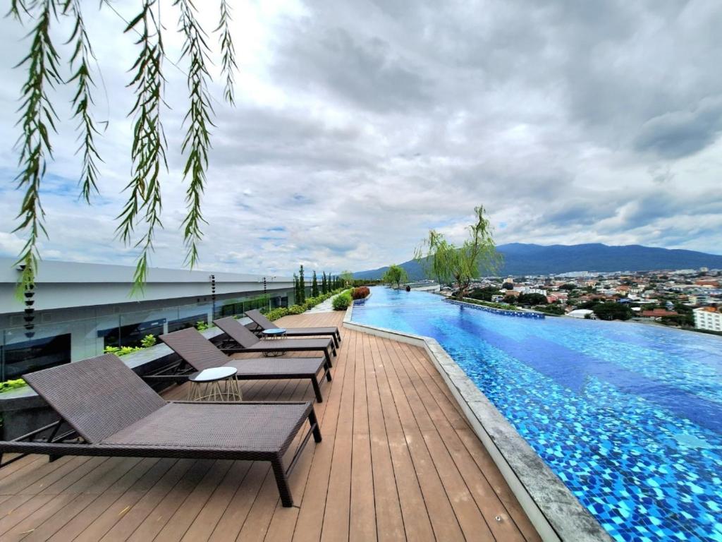 a swimming pool with chaise lounge chairs on top of a building at Astra Sky River Chiang Mai in Chiang Mai