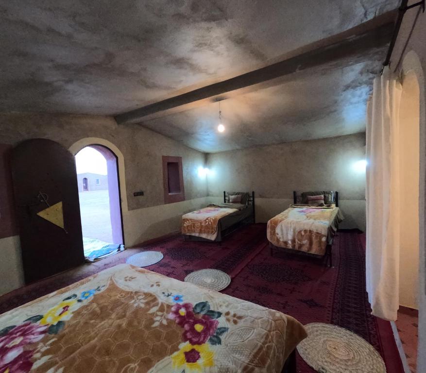 a room with two beds and a window at Sahara Luxury Camp M'hamid in Mhamid