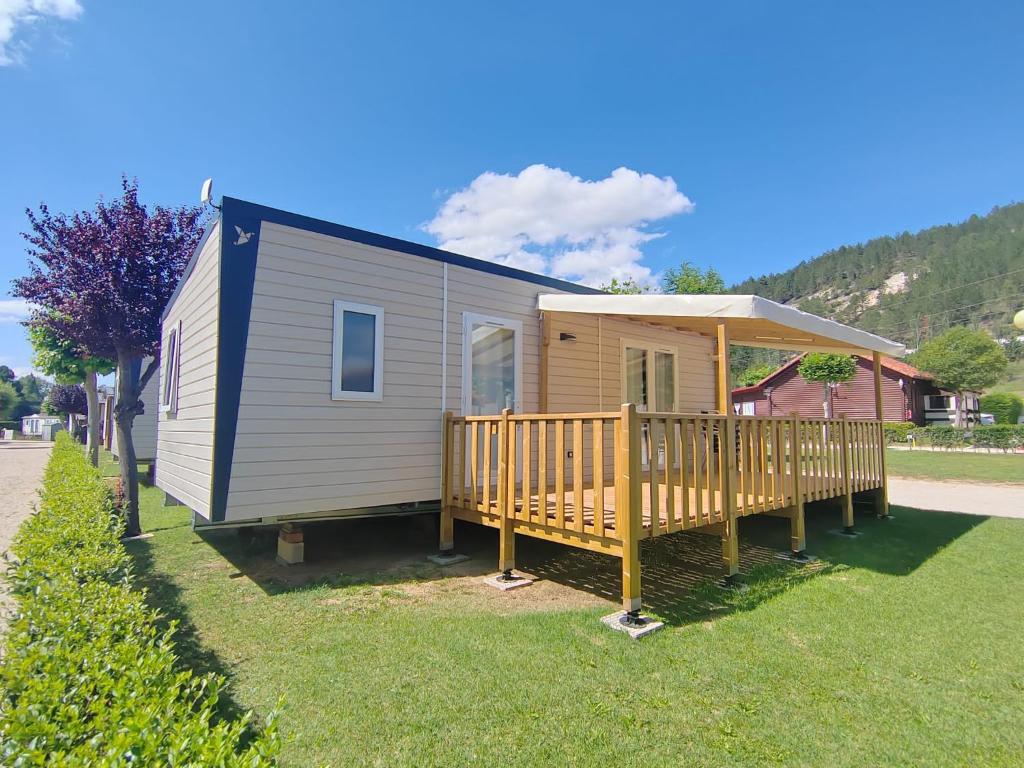 una casa pequeña con porche y terraza en Camping Rio Nela, en Trespaderne