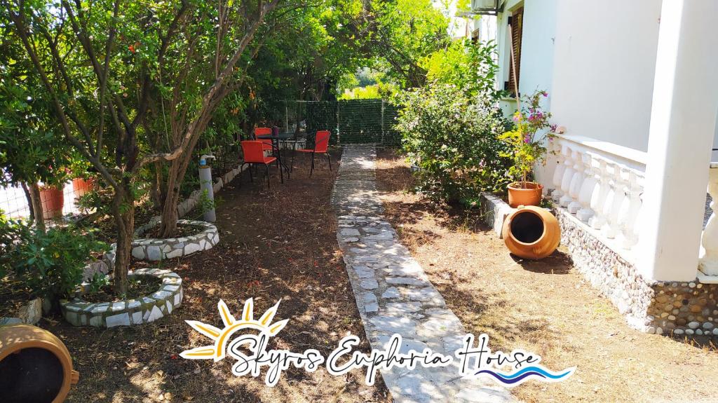 ogród z drzewami, krzesłami i ogrodzeniem w obiekcie Skyros Euphoria House w mieście Skiros