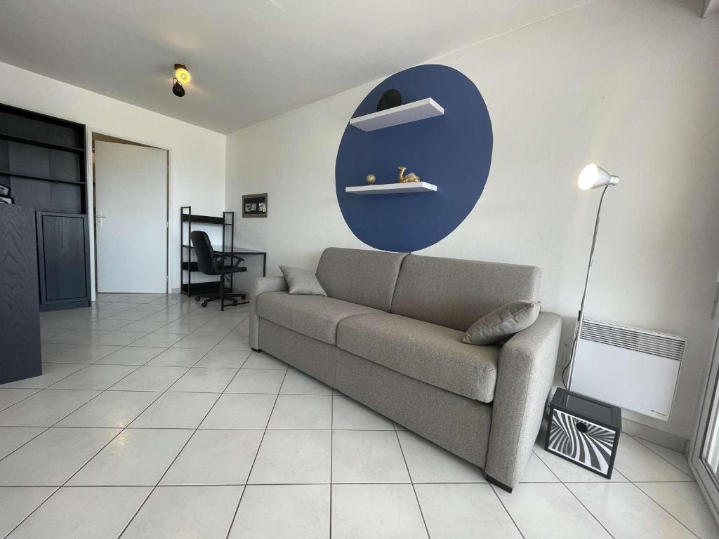a living room with a couch and a blue circle on the wall at Appartement La Rochelle, 1 pièce, 2 personnes - FR-1-246-650 in La Rochelle