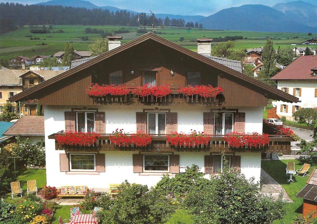 una casa con flores rojas en sus balcones en B&B Apartments Haus Gasser, en Monguelfo-Tesido