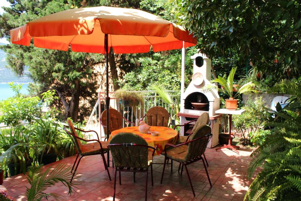 a patio with a table and an umbrella and a grill at Guest House Tomanovic in Herceg-Novi