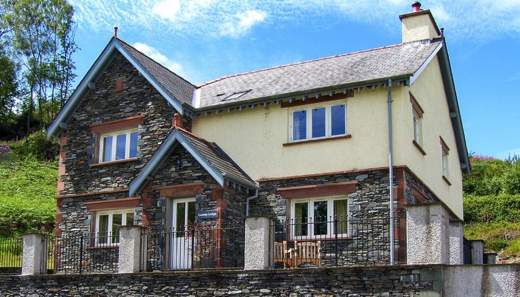 una vieja casa de piedra con una valla delante de ella en Cunsey Lodge en Far Sawrey