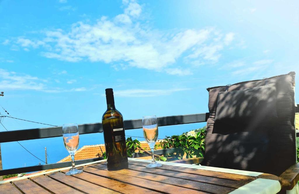 a bottle of wine and two glasses on a wooden table at Ionian Balcony in Athanion