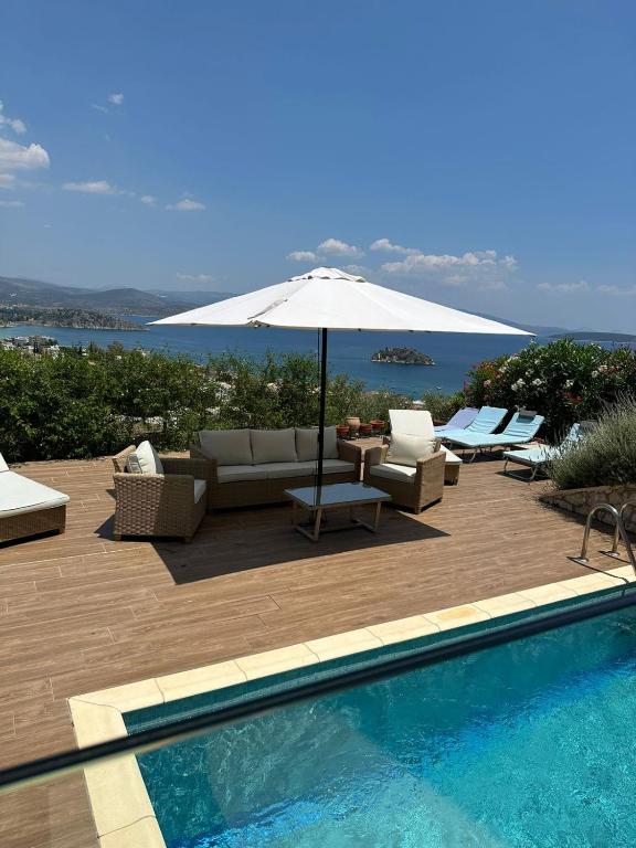 a swimming pool with an umbrella and chairs and a couch and an umbrella at Villa Natalia in Tolo